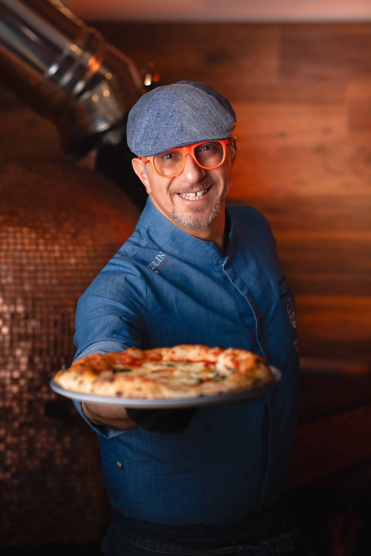 Giovanni Santarpia presenting a freshly baked pizza in front of the oven.